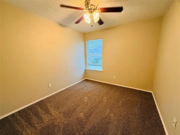 an empty room with a ceiling fan and carpet