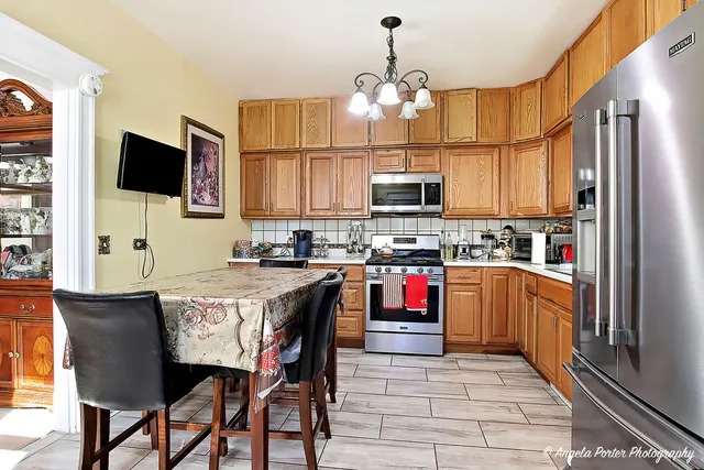 a kitchen with stainless steel appliances granite countertop a stove top oven a sink dishwasher a dining table and chairs with wooden floor