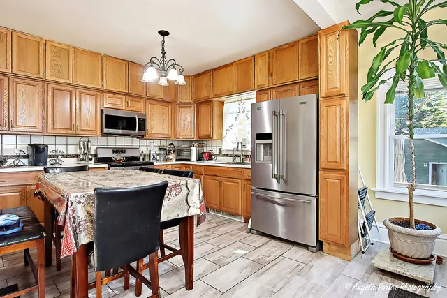 a kitchen with stainless steel appliances granite countertop a refrigerator a stove top oven a sink dishwasher and a refrigerator with wooden floor
