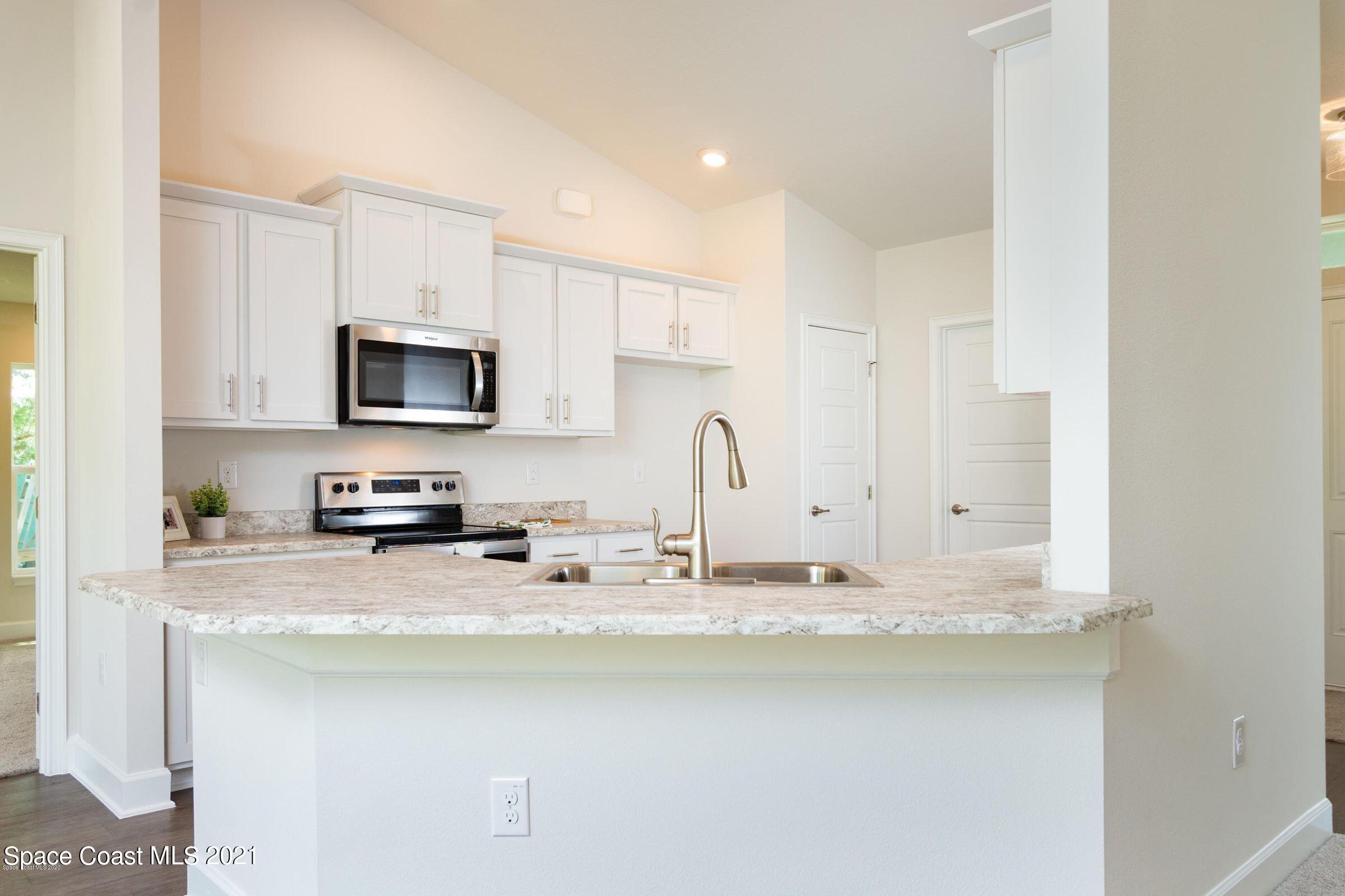 981 Degroodt Road Southwest, Unit 32 Palm Bay, FL 32908 - Photo 4 of 17 a kitchen with stainless steel appliances a sink a stove a microwave and cabinets