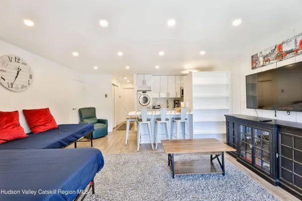 a living room with furniture a flat screen tv and kitchen view