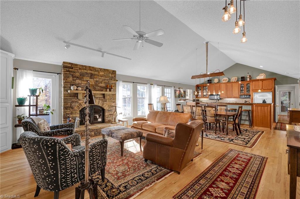 4300 Williams Road Lewisville, NC 27023 - Photo 9 of 50 Open living space with vaulted ceiling, stacked stone fireplace, wood floors