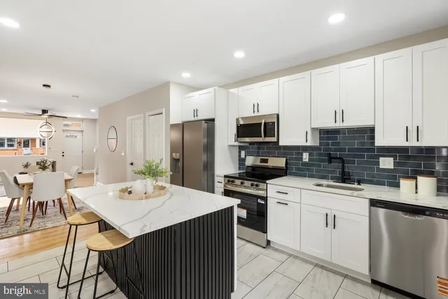 a kitchen with a sink a stove a refrigerator and white cabinets