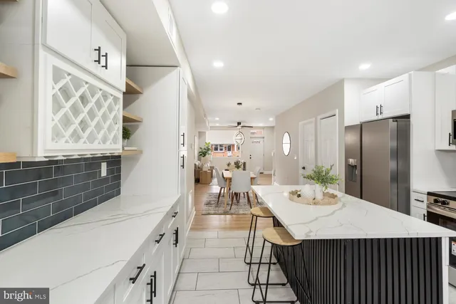 a kitchen with stainless steel appliances kitchen island granite countertop a table chairs and a refrigerator