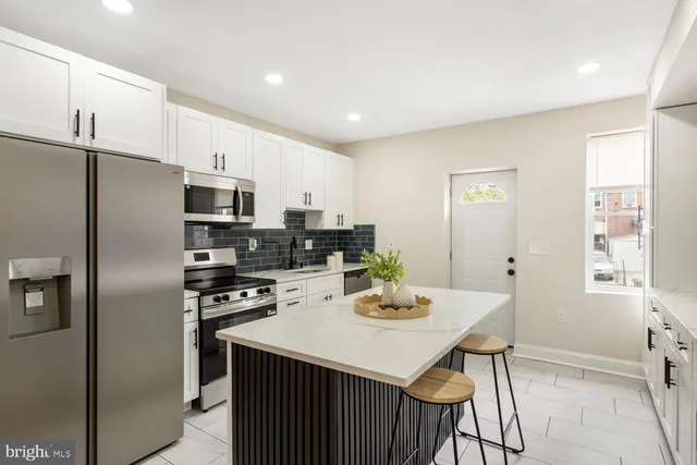 a kitchen with stainless steel appliances a sink a stove a refrigerator cabinets and dining table