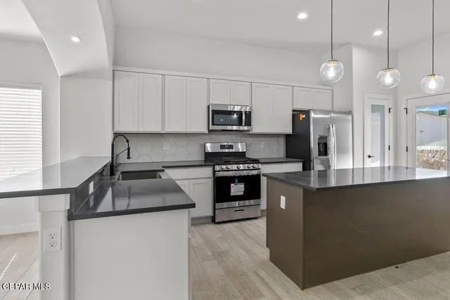 a kitchen with stainless steel appliances granite countertop a sink a stove and a refrigerator