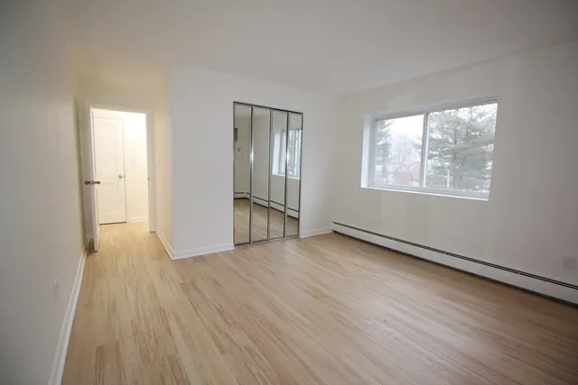 a view of an empty room with wooden floor and a window