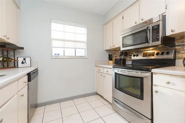 a kitchen with white cabinets stainless steel appliances and counter space