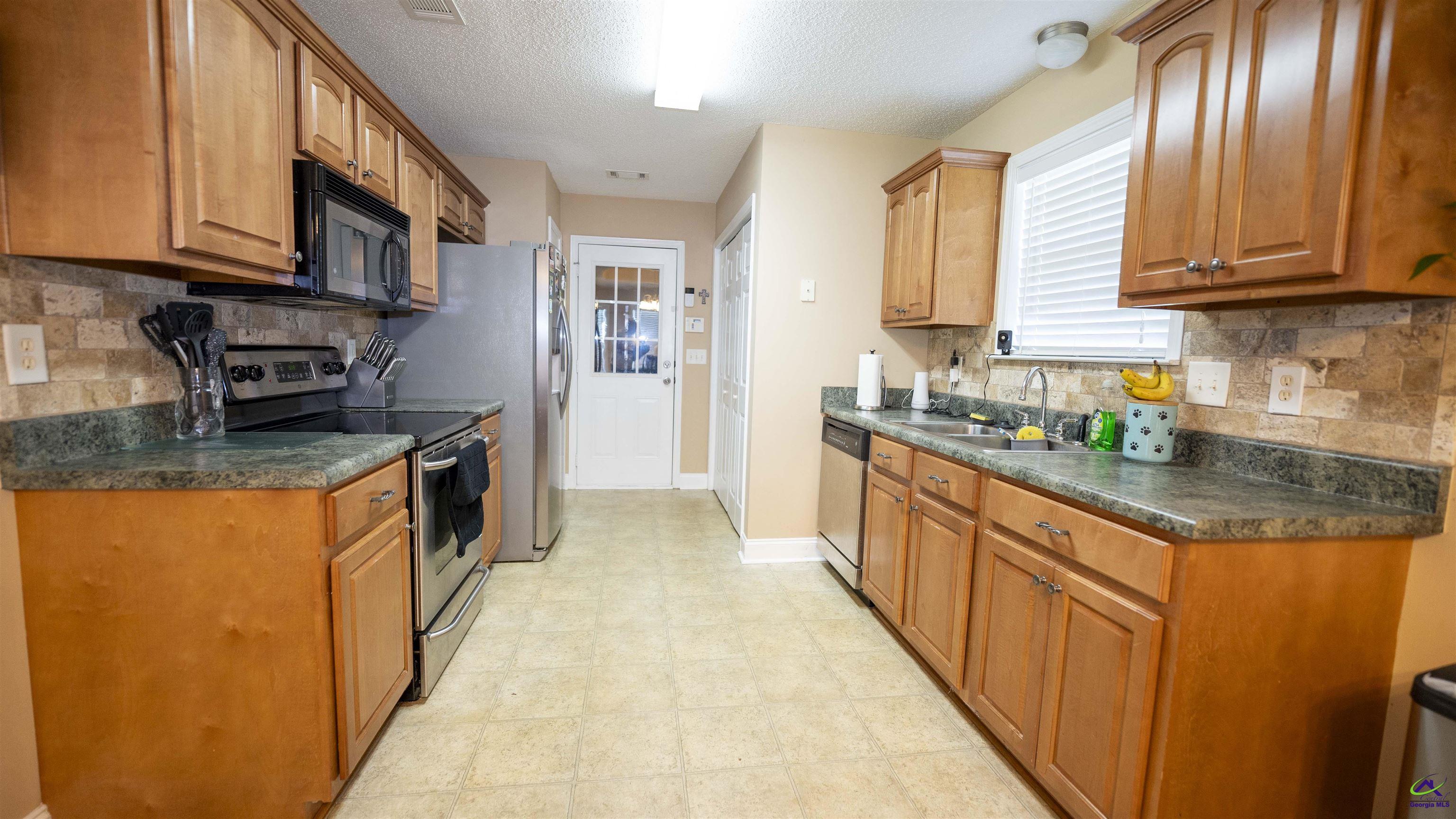311 Sugarloaf Parkway Perry, GA 31069 - Photo 8 of 31 a large kitchen with stainless steel appliances granite countertop a stove a sink and a microwave