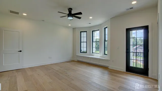 an empty room with wooden floor ceiling fan and windows