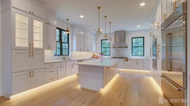 a large kitchen with kitchen island a large window a sink stainless steel appliances and cabinets