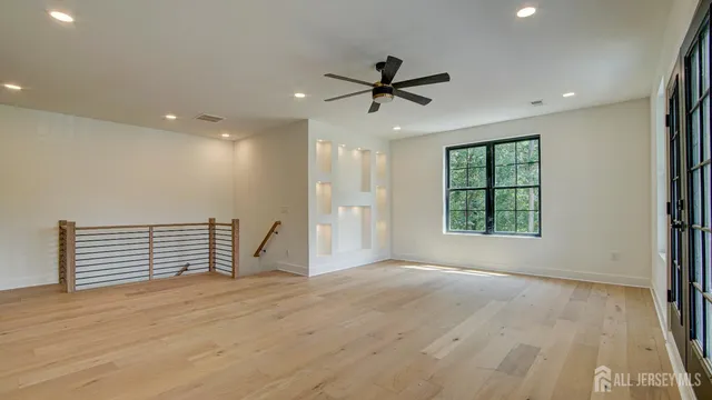 an empty room with wooden floor and a ceiling fan