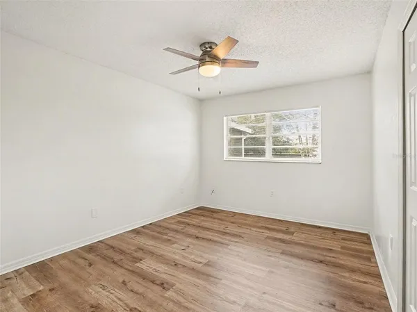 a view of empty room with wooden floor and fan