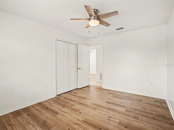 an empty room with wooden floor ceiling fan and windows