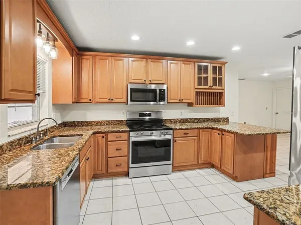 a kitchen with stainless steel appliances granite countertop a stove a sink and a microwave