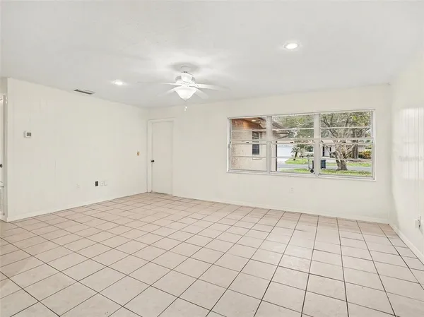 an empty room with windows and fan