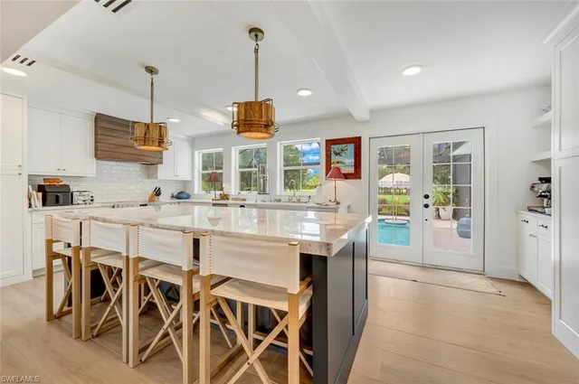 a kitchen with stainless steel appliances kitchen island granite countertop a table chairs and a wooden floor