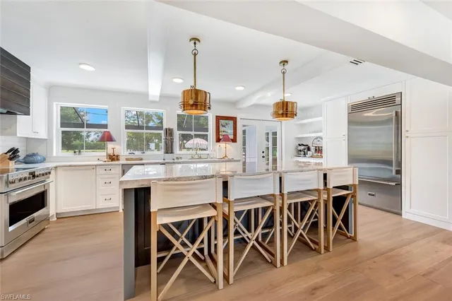 a kitchen with stainless steel appliances kitchen island granite countertop a sink a stove top oven a chimney and a center island