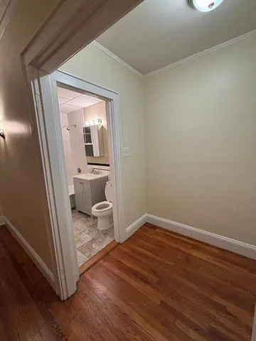 a view of a hallway with wooden floor and a bathroom