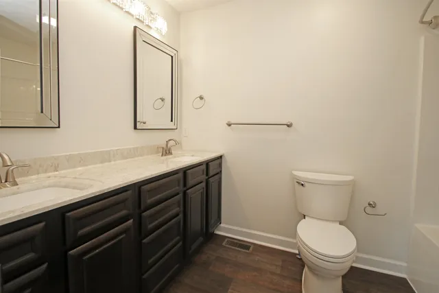 a bathroom with a granite countertop toilet sink and mirror