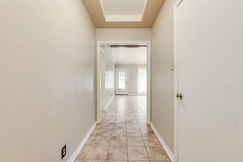 298 Butterfield Road Denison, TX 75021 - Photo 27 of 34 Hallway featuring neutral-toned walls, tile flooring, and a tray ceiling detail