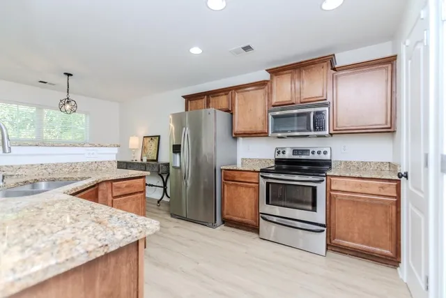 a kitchen with stainless steel appliances granite countertop a sink stove microwave and refrigerator