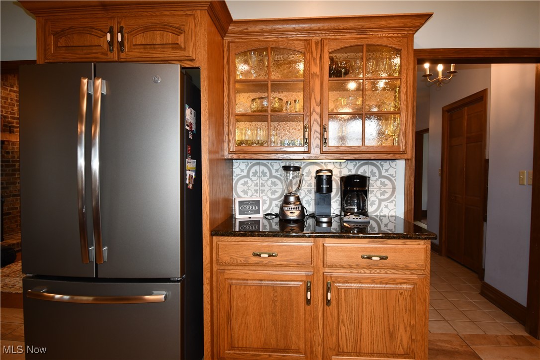 3180 West Calla Road Canfield, OH 44406 - Photo 14 of 49 Kitchen featuring freestanding refrigerator, light tile patterned floors, glass insert cabinets, brown cabinetry, and decorative backsplash