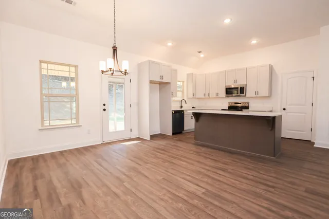 a view of a kitchen with kitchen island a sink wooden floor and a refrigerator