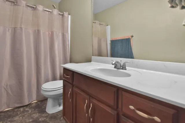 a bathroom with a granite countertop sink toilet and a mirror