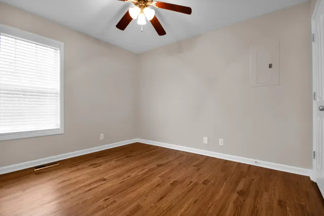 an empty room with wooden floor and windows