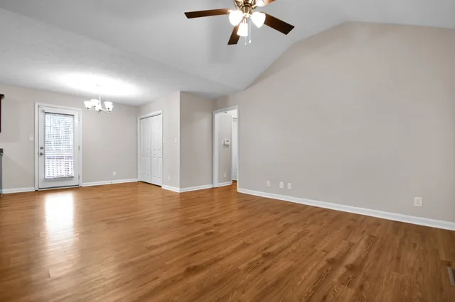 a view of an empty room with wooden floor and a ceiling fan