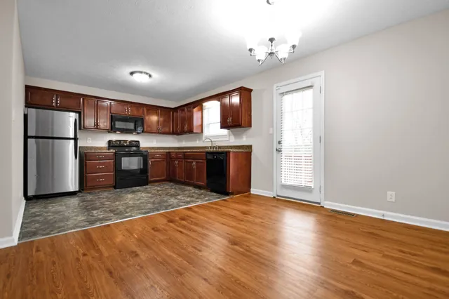 a open kitchen with kitchen island a stove a refrigerator cabinets and wooden floor