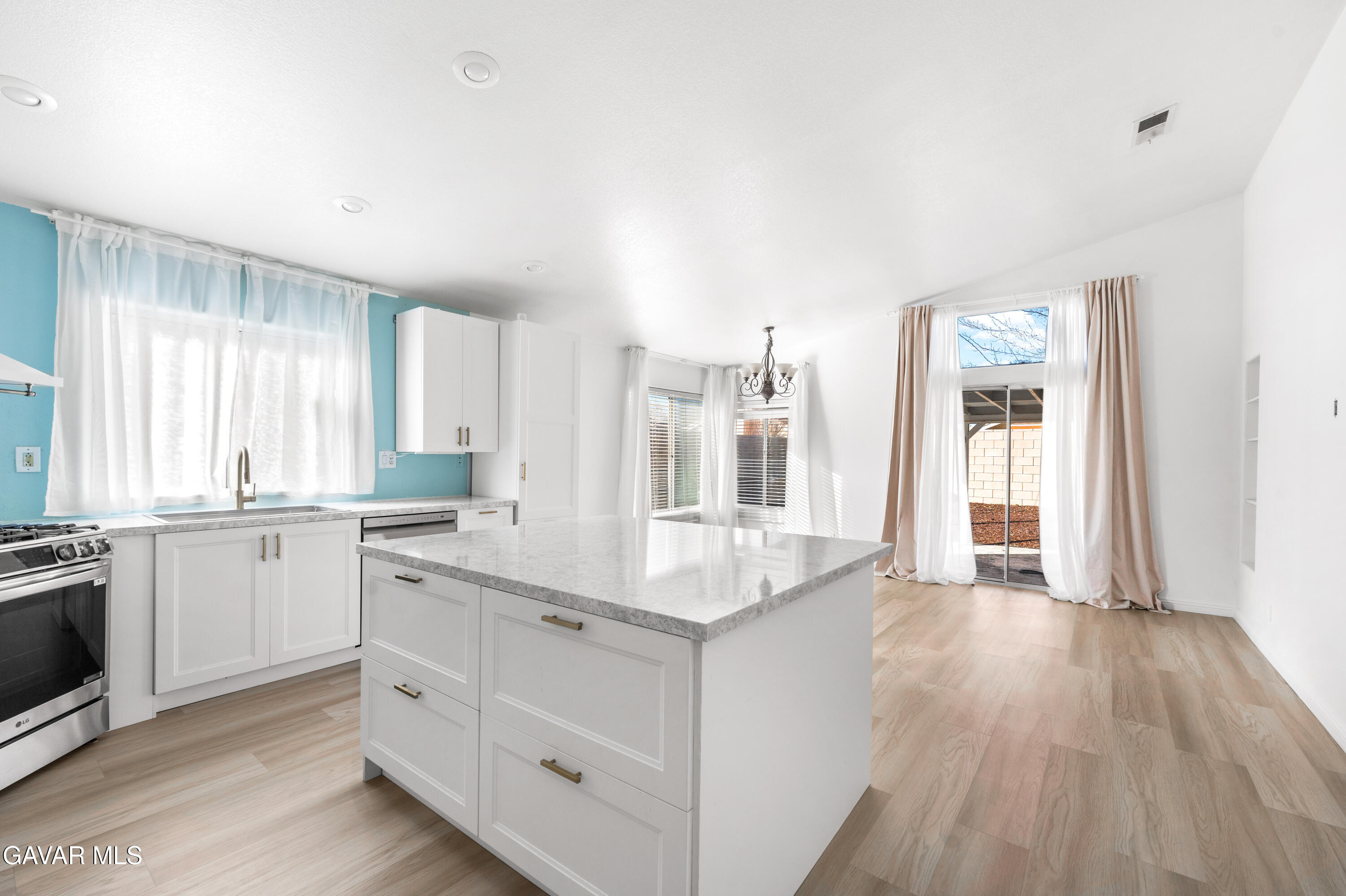 1639 East Kettering Street Lancaster, CA 93535 - Photo 12 of 35 a large white kitchen with granite countertop a stove top oven a sink and dishwasher with wooden floor