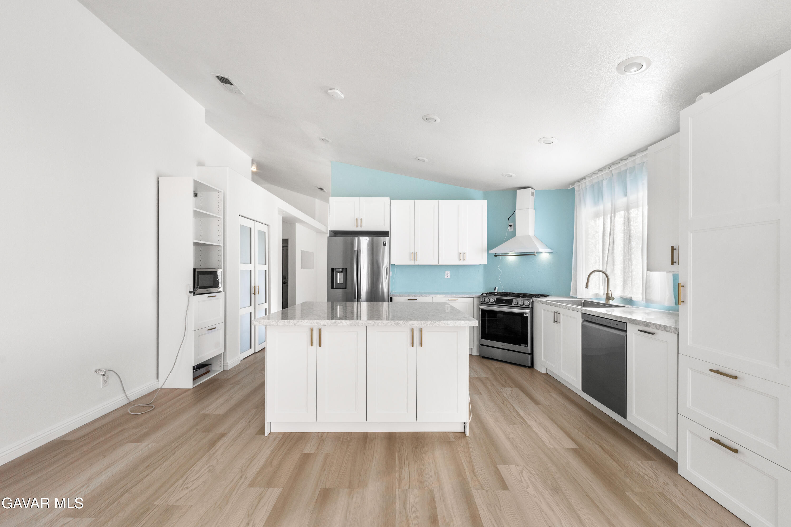 1639 East Kettering Street Lancaster, CA 93535 - Photo 14 of 35 a large kitchen with stainless steel appliances a large counter top a stove a refrigerator and white cabinets