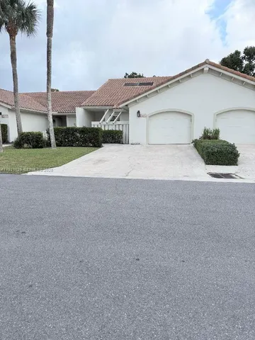 a view of a house with a yard and palm trees