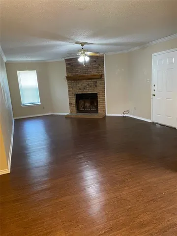an empty room with wooden floor fireplace and windows