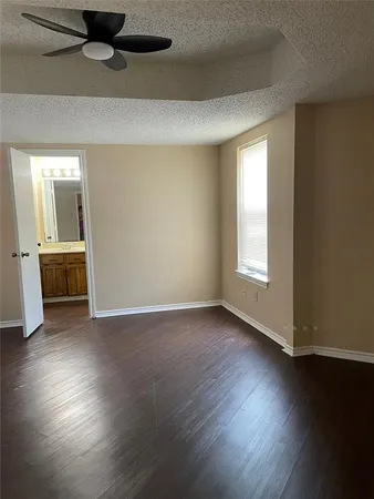 an empty room with wooden floor cabinet and windows