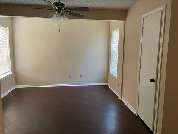an empty room with wooden floor fan and windows