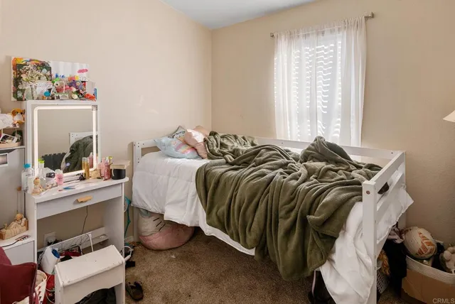 a bed sitting in a bedroom next to a window and a chair