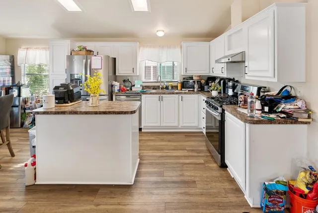 a kitchen with kitchen island a sink stove top oven and microwave