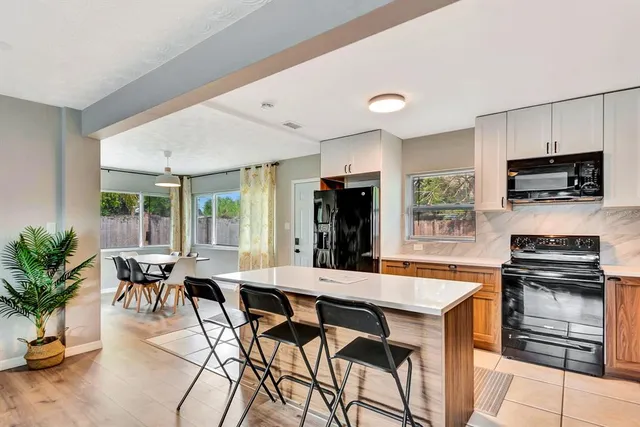 a kitchen with stainless steel appliances kitchen island granite countertop a dining table and chairs in it