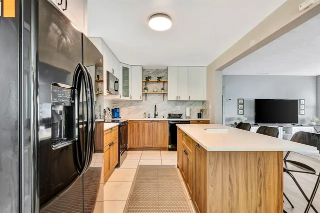 a kitchen with stainless steel appliances kitchen island granite countertop a refrigerator and a stove top oven