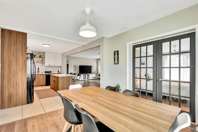 a room with stainless steel appliances kitchen island granite countertop a refrigerator a stove a sink dishwasher with a dining table and chairs with wooden floor