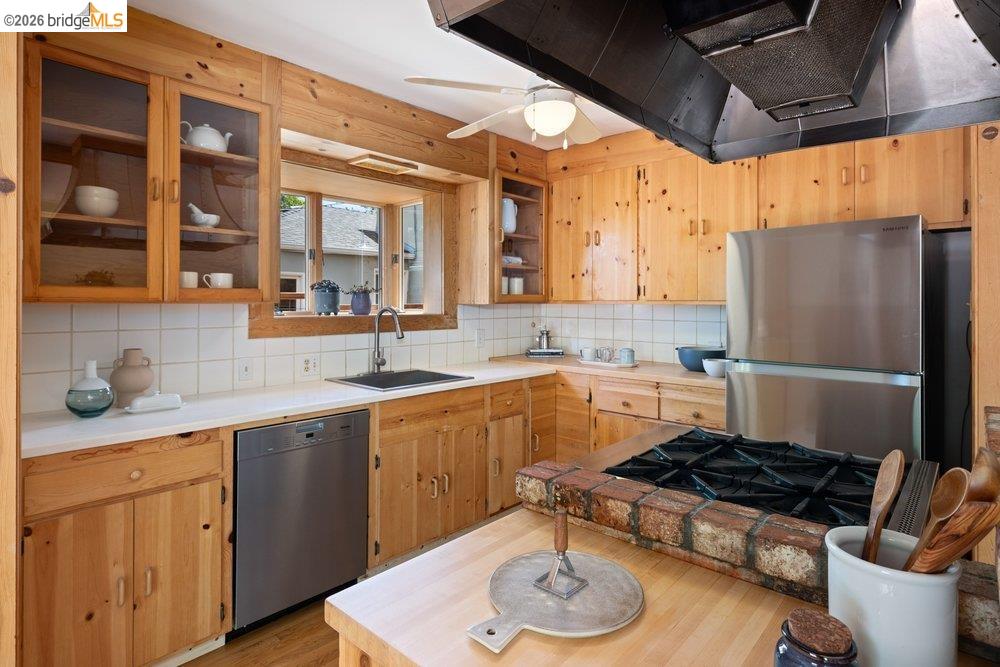 287 Purdue Avenue Kensington, CA 94708 - Photo 22 of 60 Kitchen featuring natural wood cabinetry, white countertops, tile backsplash, stainless steel appliances, and a built-in cooktop with a brick surround