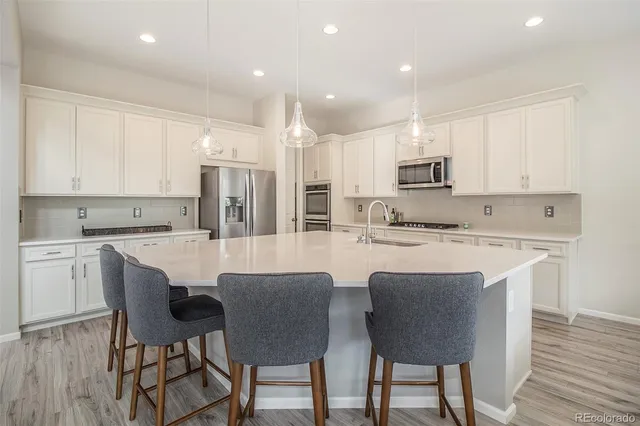 a kitchen with kitchen island granite countertop a dining table chairs and white cabinets