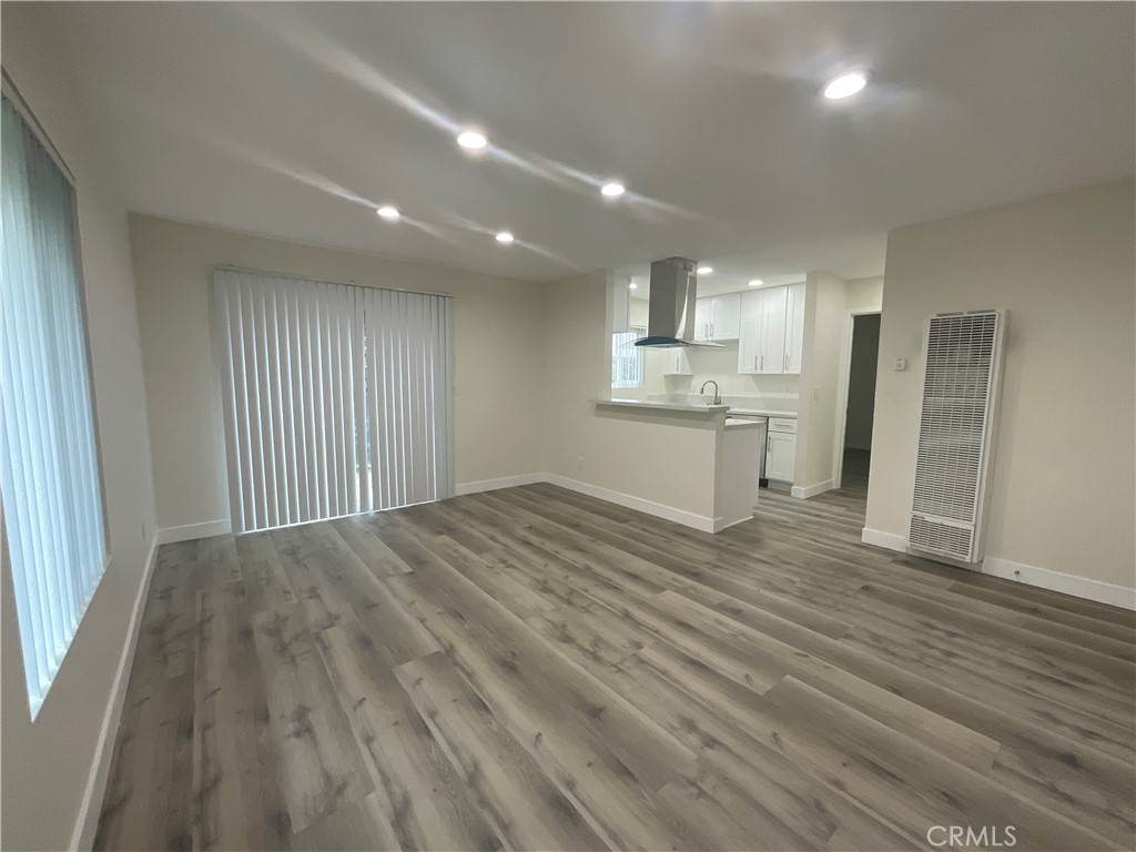 16862 Green, Unit 2 Huntington Beach, CA 92649 - Photo 4 of 13 an empty room with wooden floor and kitchen view
