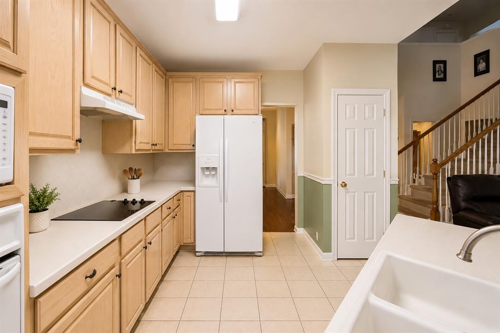 1508 Valley Creek Road Denton, TX 76205 - Photo 15 of 33 a kitchen with granite countertop a refrigerator a sink and white cabinets