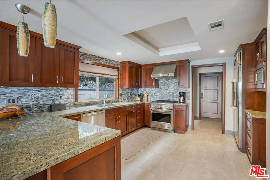18074 Coastline Drive Malibu, CA 90265 - Photo 19 of 33 a kitchen with stainless steel appliances granite countertop a sink and a refrigerator