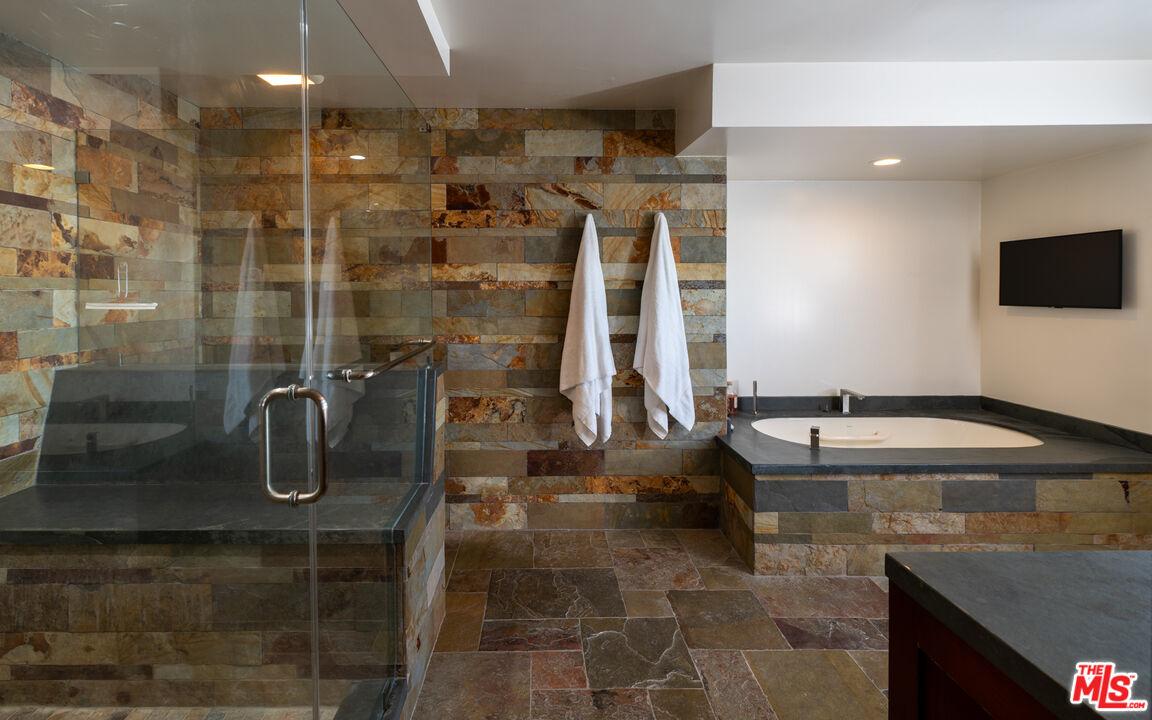 18074 Coastline Drive Malibu, CA 90265 - Photo 24 of 33 a bathroom with a granite countertop sink a mirror and shower