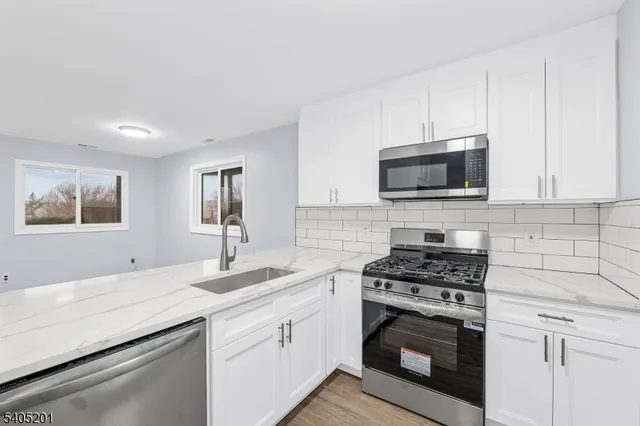 a kitchen with cabinets stainless steel appliances a sink and a stove